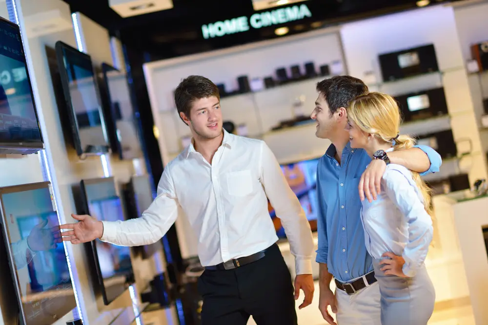 young couple in electrical store looking at TVs