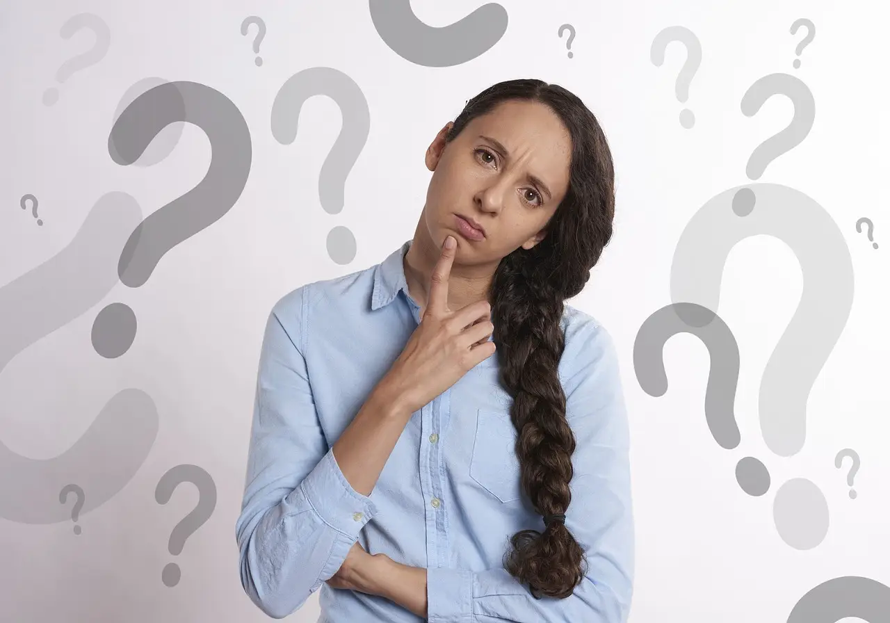 Young lady pondering with finger on chin surrounded by question marks